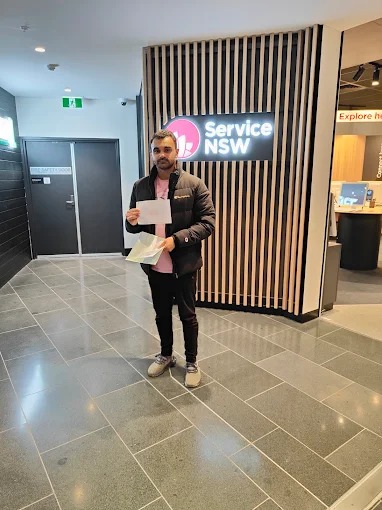 Student leaving a Service NSW centre with driving test paperwork after passing