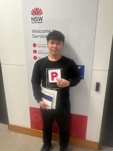 Student holding red P plates and paperwork at a Service NSW centre after passing the driving test