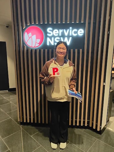 Student holding red P plates and paperwork at a Service NSW centre after passing the driving test