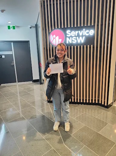 Student holding a pass certificate at a Service NSW centre after passing the driving test